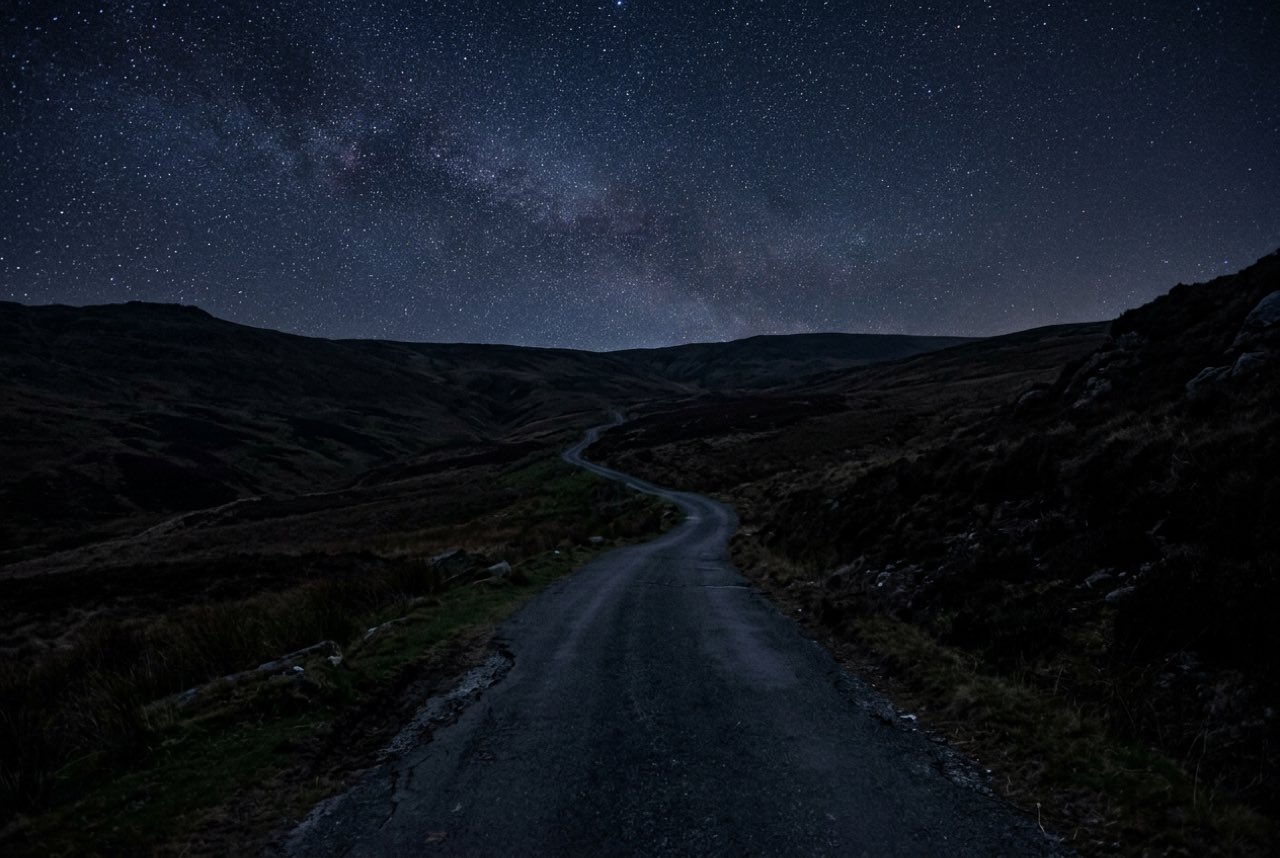 Three in the morning: an upland road under a clear night sky, the hills black, no light source but the sky itself